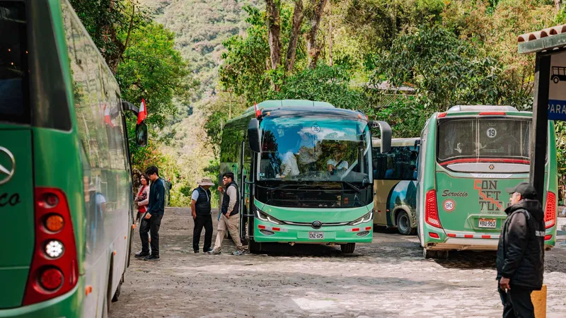 Official Machu Picchu shuttle bus boarding travelers in Aguas Calientes, Peru