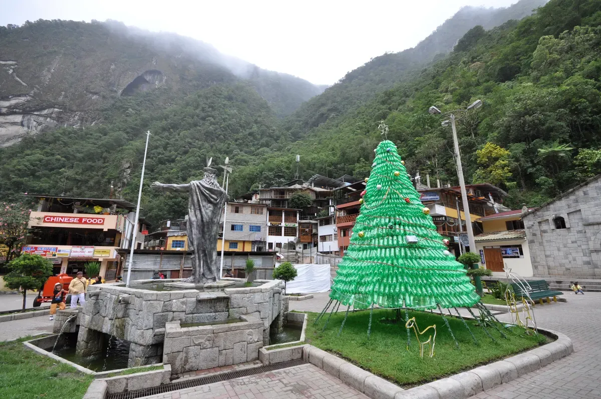 The statue of the Inca ruler Pachacutec on the Plaza de Armas of Aguas Calientes, Peru, with the forested gorge wall behind